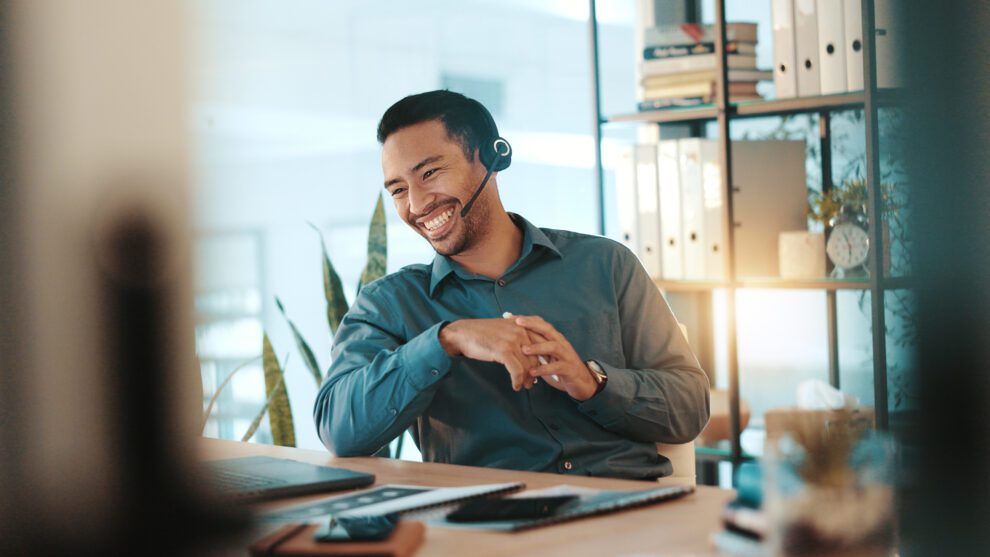 Conseiller souriant avec casque-micro à son bureau, en accompagnement client.