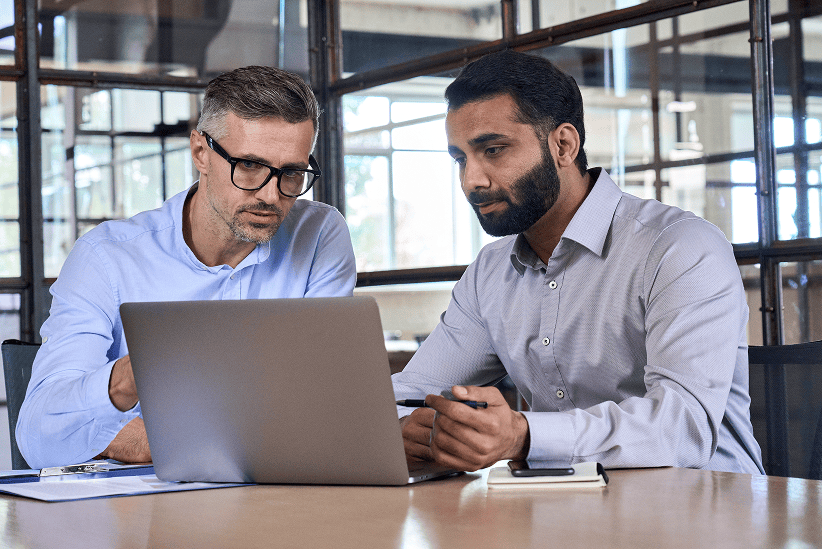 Deux professionnels concentrés analysant ensemble le contenu d'un ordinateur portable au bureau.