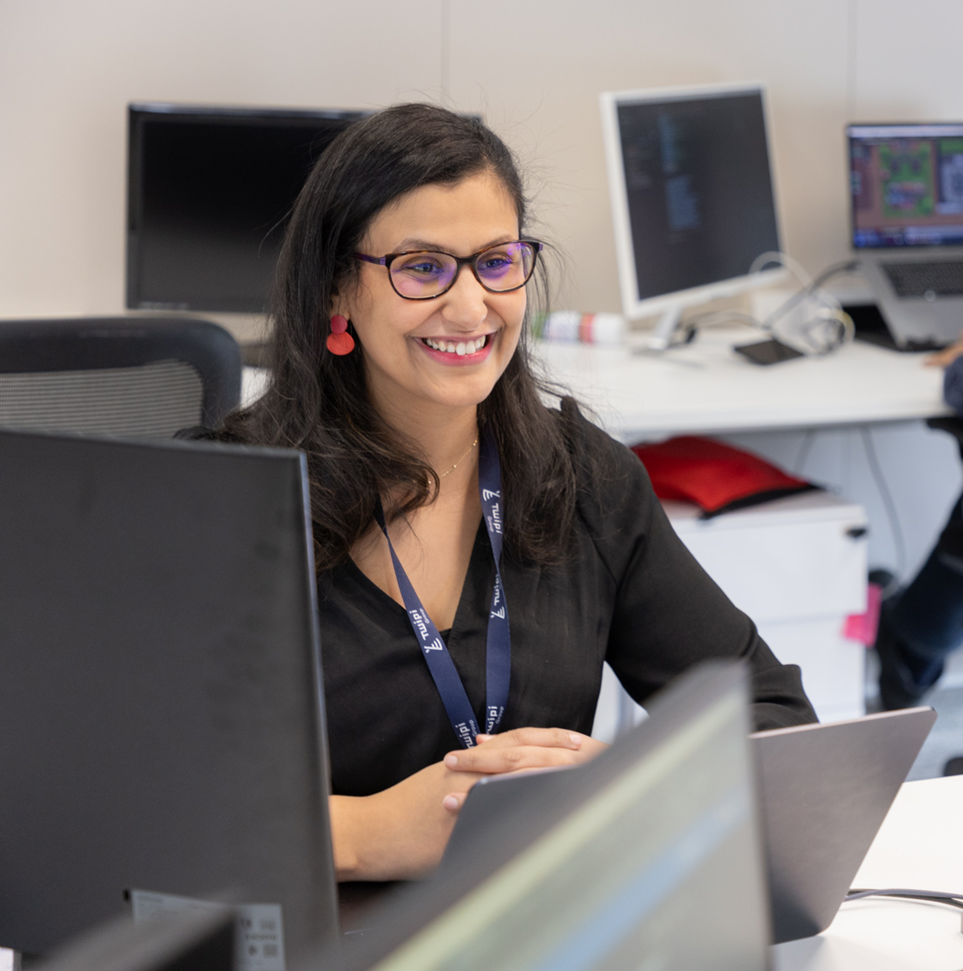 Collaboratrice de Twipi Group souriante à son poste de travail devant ses écrans.