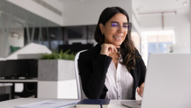 Femme cadre souriante en tailleur travaillant sur son ordinateur portable au bureau.