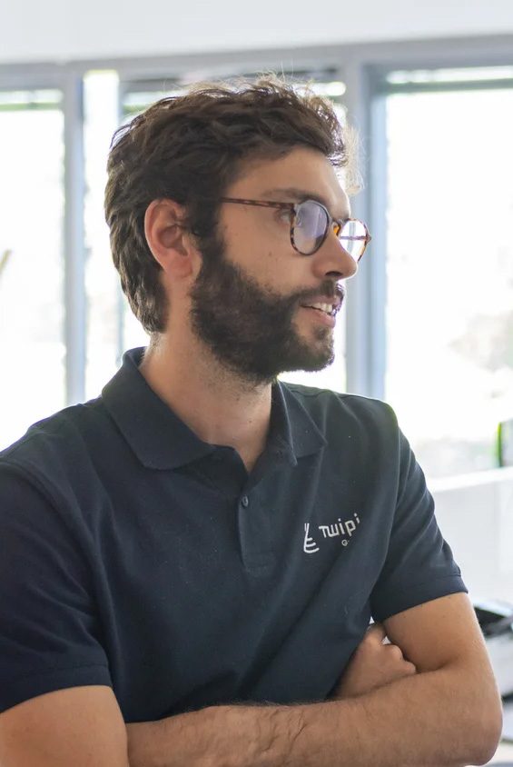 Nous rejoindre 2 Portrait d'un collaborateur de Twipi Group en polo aux couleurs de la marque, au bureau.